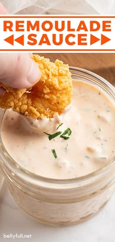 a person dipping some food into a small glass bowl with ranch dressing in the background