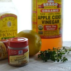 three jars of apple cider vinegar next to an orange and some herbs on a table