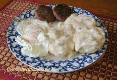 a plate with eggs, meatballs and gravy on it sitting on a place mat