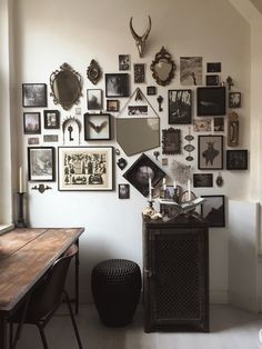 a room filled with lots of framed pictures on the wall next to a wooden table