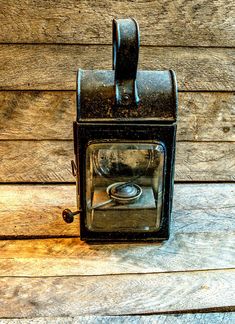 an old fashioned camera sitting on top of a wooden table next to a wall with wood planks