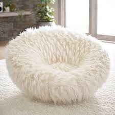 a fluffy white dog bed sitting on top of a rug