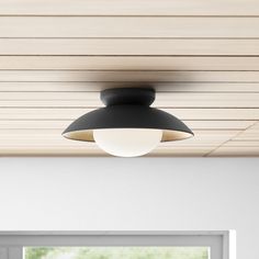 a black and white light hanging from the ceiling in a room with wood paneling