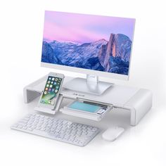 a computer desk with a keyboard, mouse and cell phone on it in front of a monitor