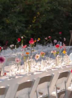 the tables are set with clear vases filled with colorful flowers and place settings for guests to sit at