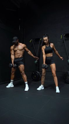 a man and woman standing next to each other in front of a gym equipment rack