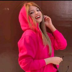 a girl in a pink hoodie talking on her cell phone