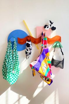 several pieces of colorful cloth hanging on a white wall next to a pair of scissors