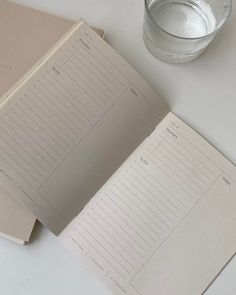 an open notebook next to a glass of water