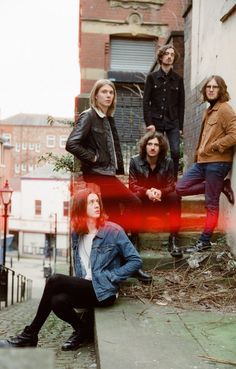 a group of people sitting on the side of a building next to each other in front of a brick wall