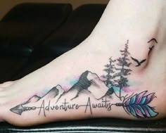 a foot tattoo with an arrow and mountains on the bottom, which reads adventure await