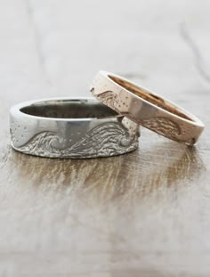 two wedding rings sitting on top of a wooden table next to each other and one has an engraved band