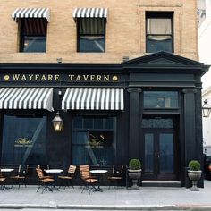 an empty sidewalk in front of a restaurant with awnings on the windows and tables outside