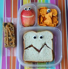 a plastic container filled with food and two eyes drawn on the side, along with pretzels