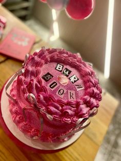 there is a pink cake that has been decorated with letters and flowers on the top