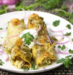 an enchilada on a white plate with onions and cilantro garnish