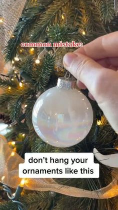 someone is holding an ornament in front of a christmas tree with the caption, don't hang your ornaments like this