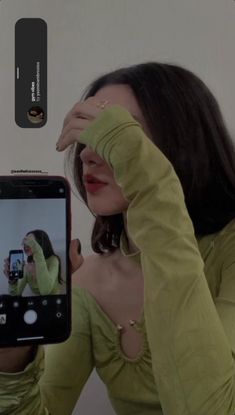 a woman taking a selfie with her cell phone in front of her face and holding up the camera