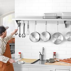 a man standing in front of a kitchen counter with pots and pans hanging on the wall