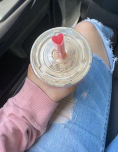 a person holding a drink in their hand with a red cap on it's head