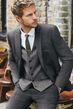 a man wearing a suit and tie sitting on a bench