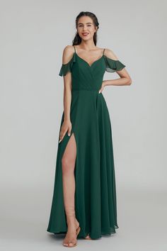 a woman in a long green dress with one leg slited up and her legs crossed out