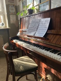 an old piano with sheet music sitting on it's stand next to a chair