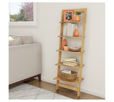 a wooden shelf with books and vases on it in front of a white couch