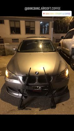 a silver car parked in front of a building at night with its lights turned on