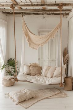 a white bedroom with a bed, rugs and pillows on the floor in front of a window