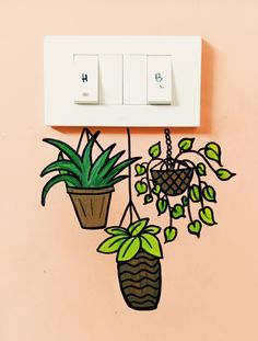 a wall mounted light switch with plants on it and two potted plants hanging from the outlet