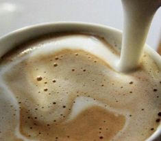 milk being poured into a cup of coffee