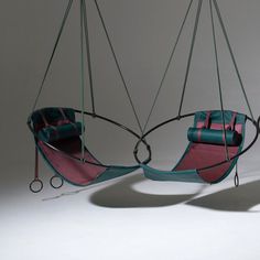 two hanging chairs with pink and blue cushions on them, one in the shape of a hammock