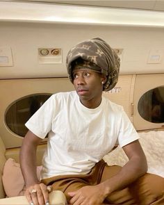 a man sitting on top of a bed wearing a hat