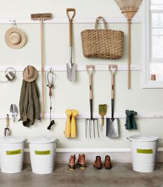 several buckets, shovels and gardening implements are hanging on the wall next to each other