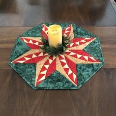 a candle is lit on a green table with red and white quilted star design