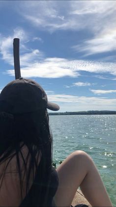 a woman sitting on top of a wooden pier next to the ocean