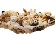 a bunch of stuffed animals sitting in a net on top of a table with a gray background