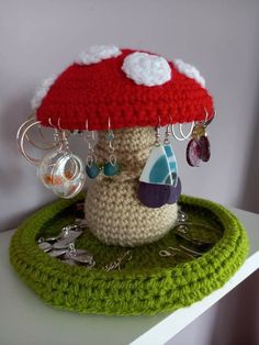 a crocheted mushroom hat on top of a green object with earrings hanging from it