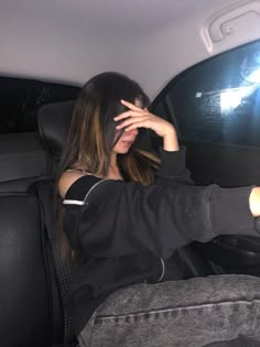 a woman sitting in the back seat of a car with her hand on her head