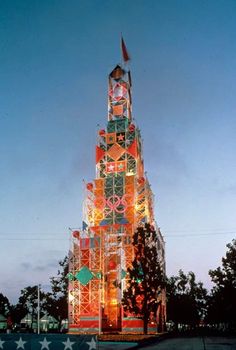 a tall tower with many lights on it's sides and trees in the background