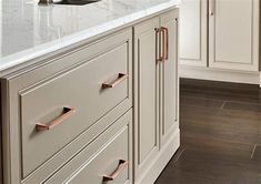 a kitchen with white cabinets and marble counter tops