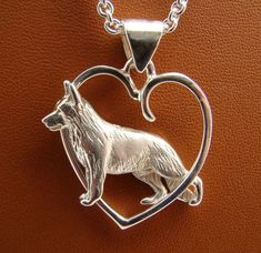 a heart shaped pendant with a wolf on it's front and back ends in the shape of a heart