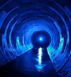 a blue tunnel with water in the middle and light coming from it's end