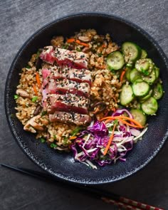 a black bowl filled with meat, rice and veggies