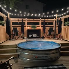 an outdoor hot tub is lit up with lights and string lights on the outside wall