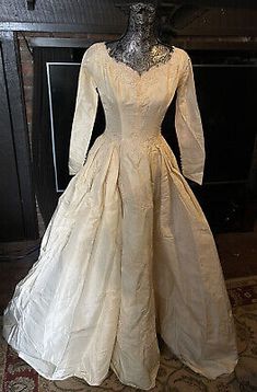 an antique wedding dress on display in front of a fireplace