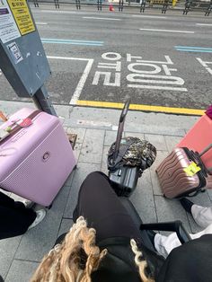 several pieces of luggage sitting on the ground near a bus stop with people walking by