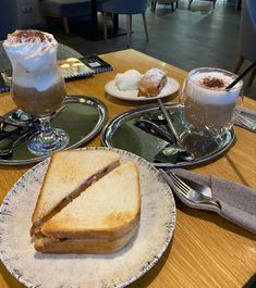 two plates with sandwiches and drinks on them sitting on a table in front of the camera