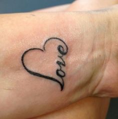 a small black heart tattoo on the wrist